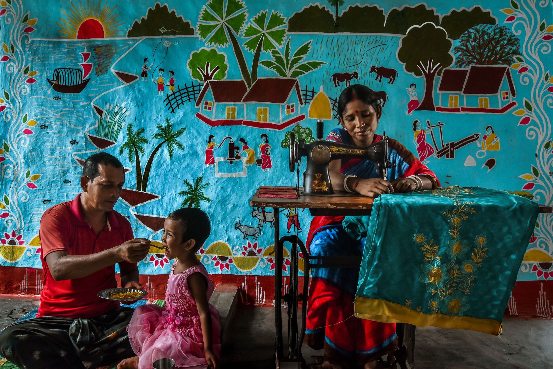 A family at home — mother tailoring, father and daughter sharing a meal